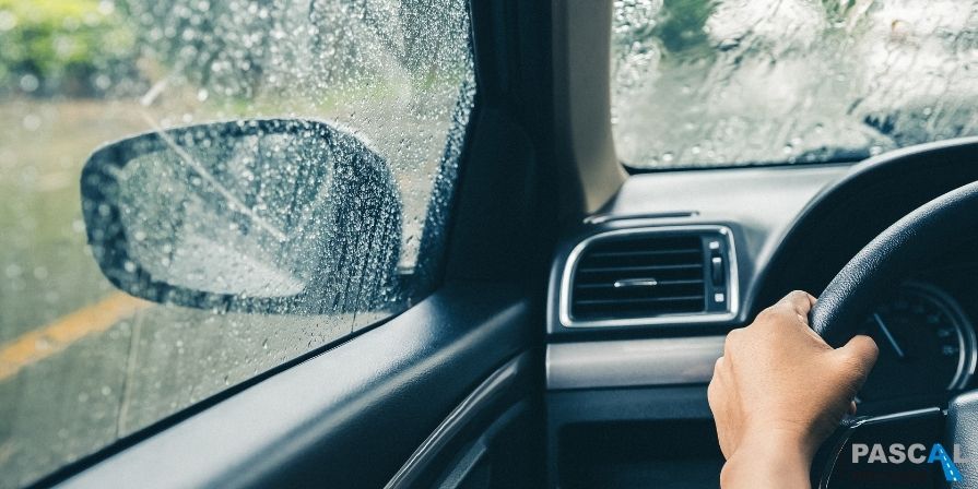 Vrouw achter het stuur aan het autorijden de regen